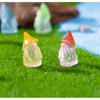 Three luminous resin mini fairy gnomes in yellow, green, and orange standing on bright green grass.