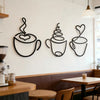 Un juego de tres piezas de decoración de pared de tazas de café de hierro negro, exhibidas en una pared blanca sobre un mostr
