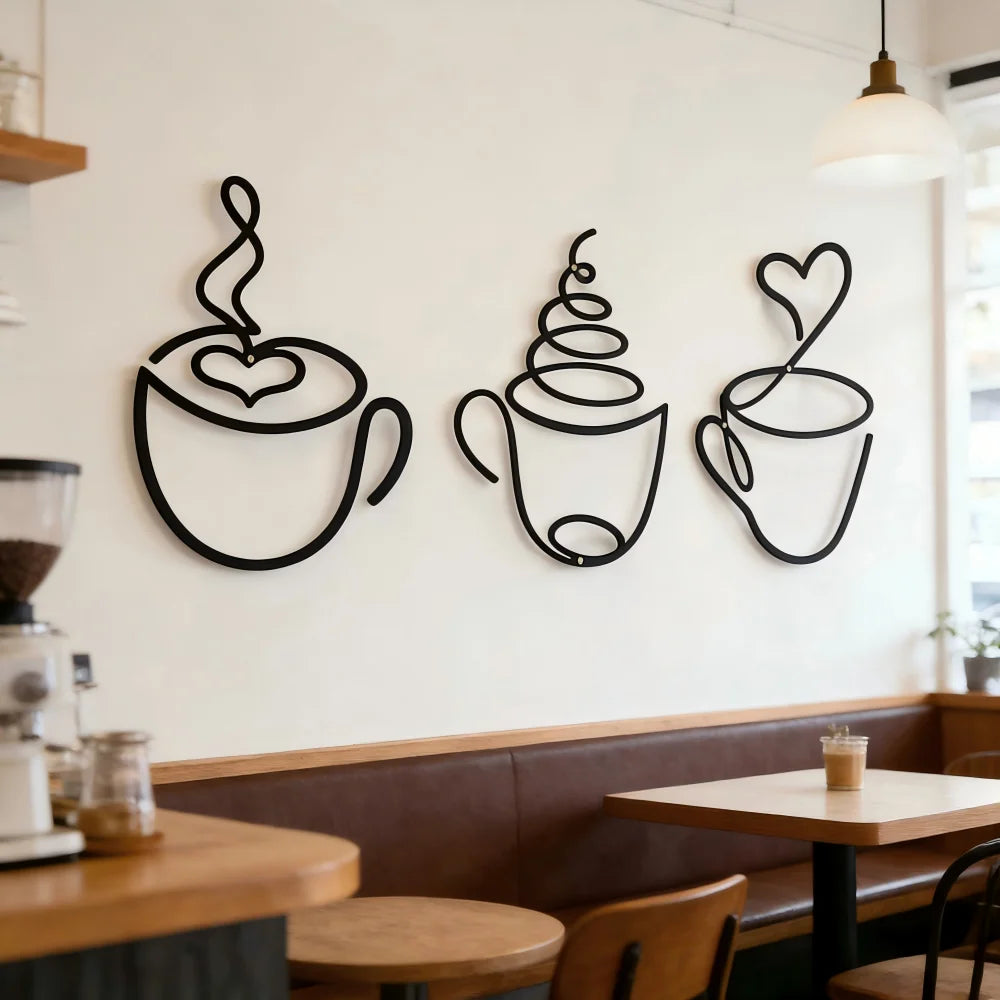 Un juego de tres piezas de decoración de pared de tazas de café de hierro negro, exhibidas en una pared blanca sobre un mostr