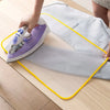 A purple heat resistant ironing cloth is being used with a steam iron on a light wooden table.