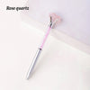 A silver crystal pen with a pink rose quartz gemstone is displayed on a white surface.
