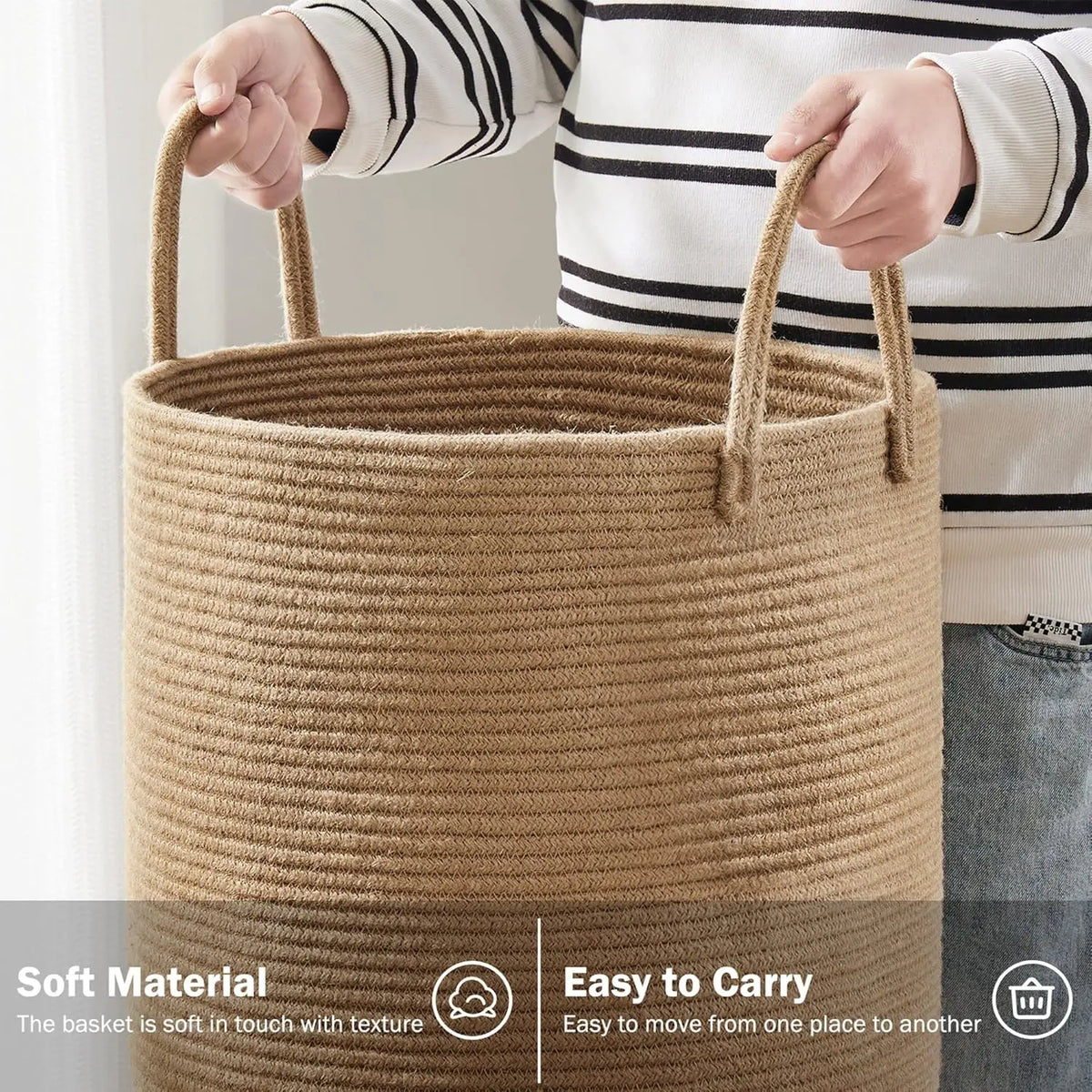 A person is holding a large woven storage hamper made of natural fiber with handles.