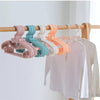 A row of colorful plastic clothes hangers are displayed on a wooden rack.
