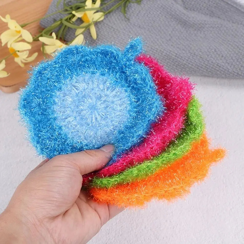 A hand holds a stack of colorful, fluffy non-stick acrylic dish towels in various shades of blue, pink, green, and orange.