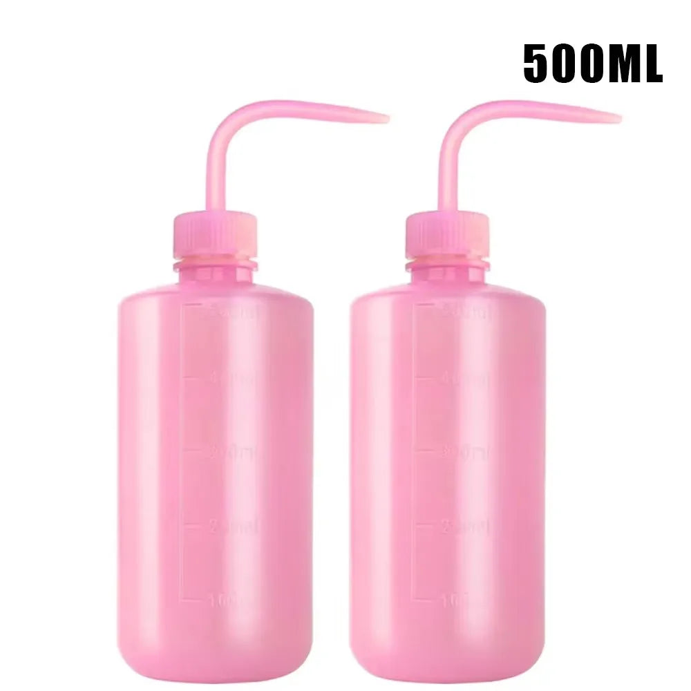 A pair of pink 500ml squeeze bottles with measurement marks for tattoo solutions.
