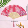 Pink lace fabric folding hand fan with pink and white floral designs shown against a light pink background.