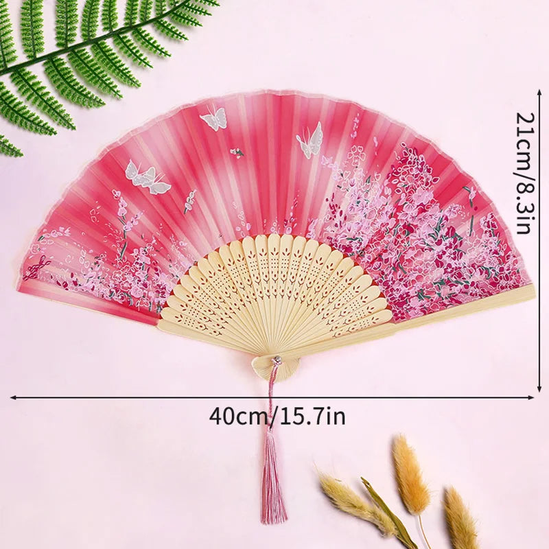 Pink lace fabric folding hand fan with pink and white floral designs shown against a light pink background.