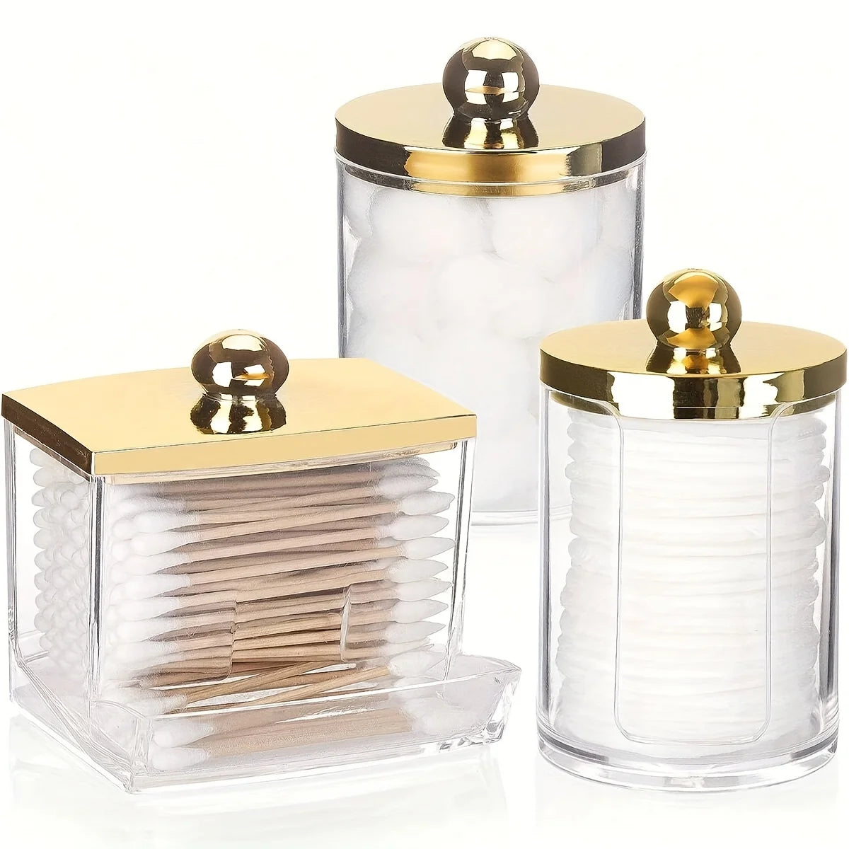 A clear glass apothecary jar dispenser with a golden lid holding cotton balls and swabs.