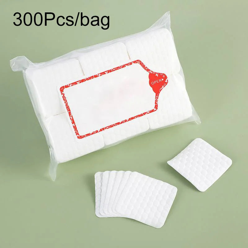 A clear plastic bag containing 300 cotton pads for nail and gel polish removal, with several loose pads displayed nearby.