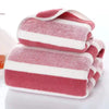 A set of folded pink and white striped microfiber bath towels.