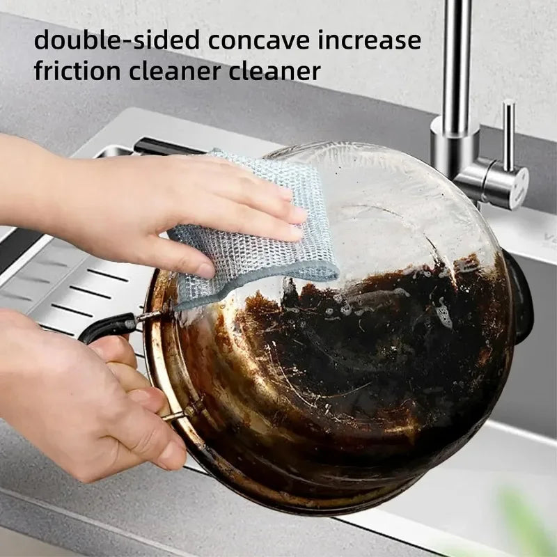 Hands are cleaning a dark pot with a double-sided concave friction cleaner tool.