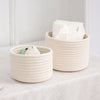 A natural beige handwoven cotton rope storage basket filled with white tissue paper.