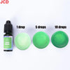 A bottle of grass green liquid candle dye next to three circular discs showing 1, 5, and 10 drops of the color.