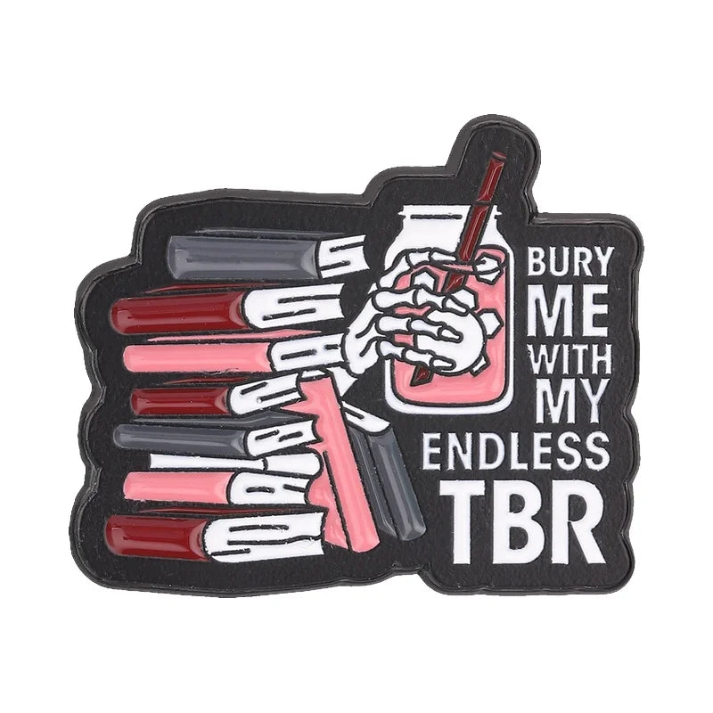 Insignia de esmalte negro con una mano sosteniendo un vaso de líquido rojo y varios bolígrafos, con el texto 'Entiérrenme con