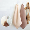 A set of four absorbent 100% cotton waffle weave towels in beige and taupe colors hanging on a white wall.