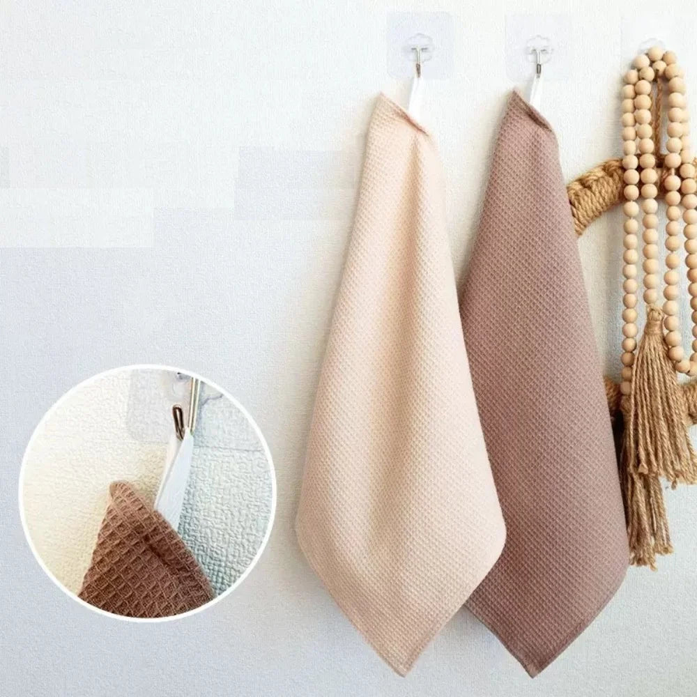 A set of four absorbent 100% cotton waffle weave towels in beige and taupe colors hanging on a white wall.