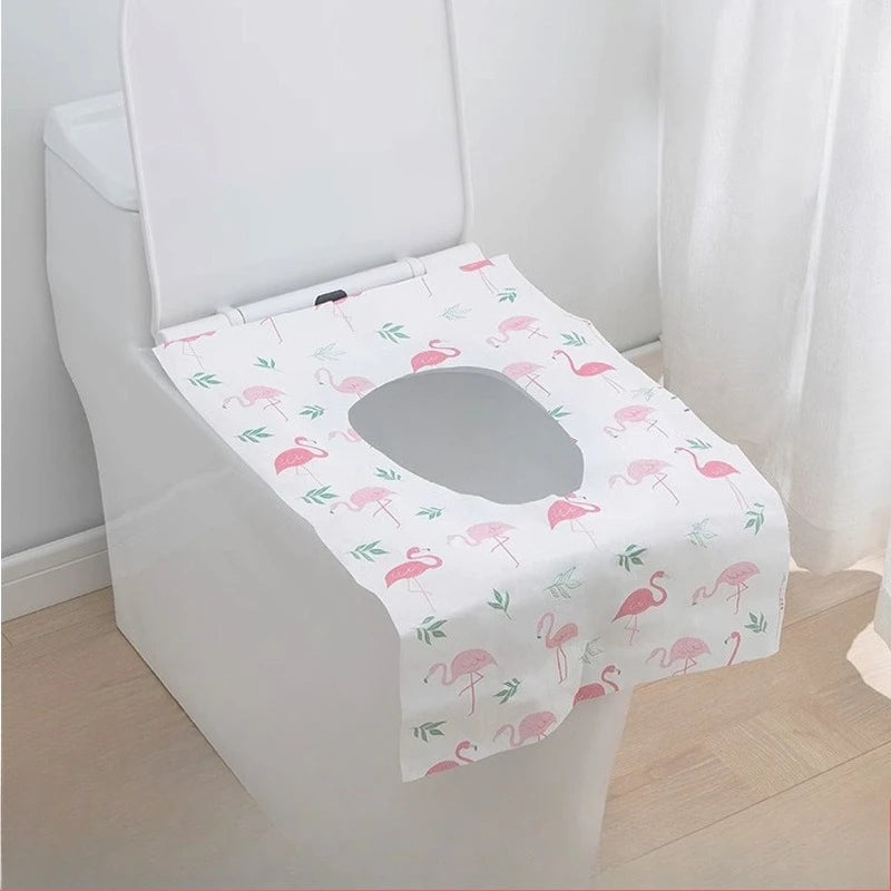 A white toilet seat covered with a pink flamingo patterned disposable printing seat cover.