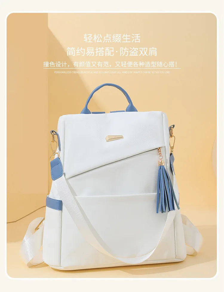 A white women's anti-theft PU leather travel backpack with blue accents and tassel details.