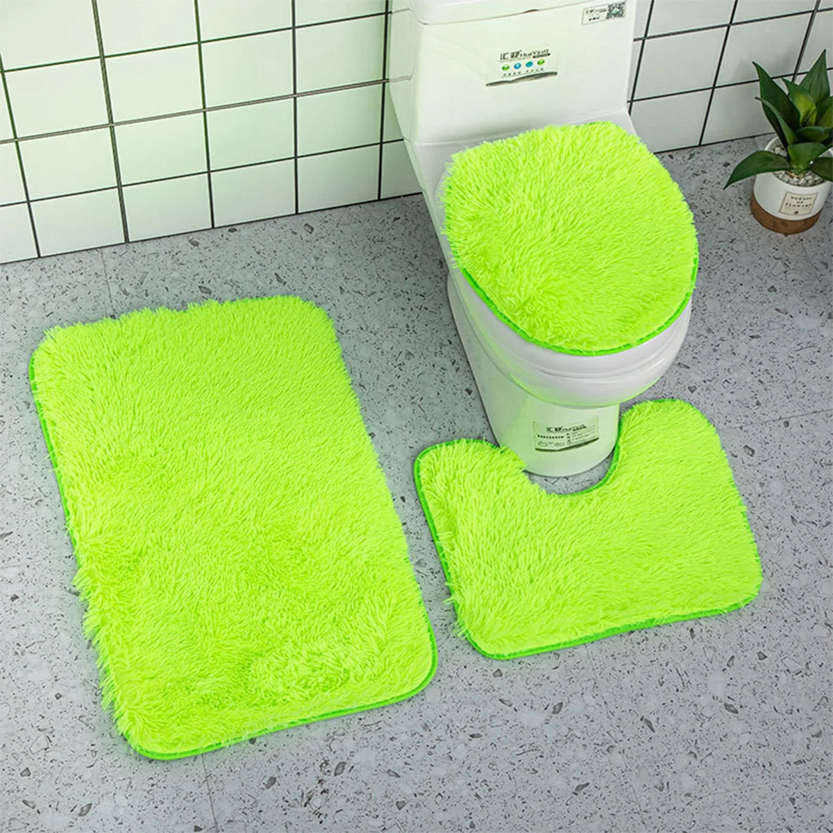 A set of three bright lime green super soft non-slip bathroom rugs displayed next to a toilet.