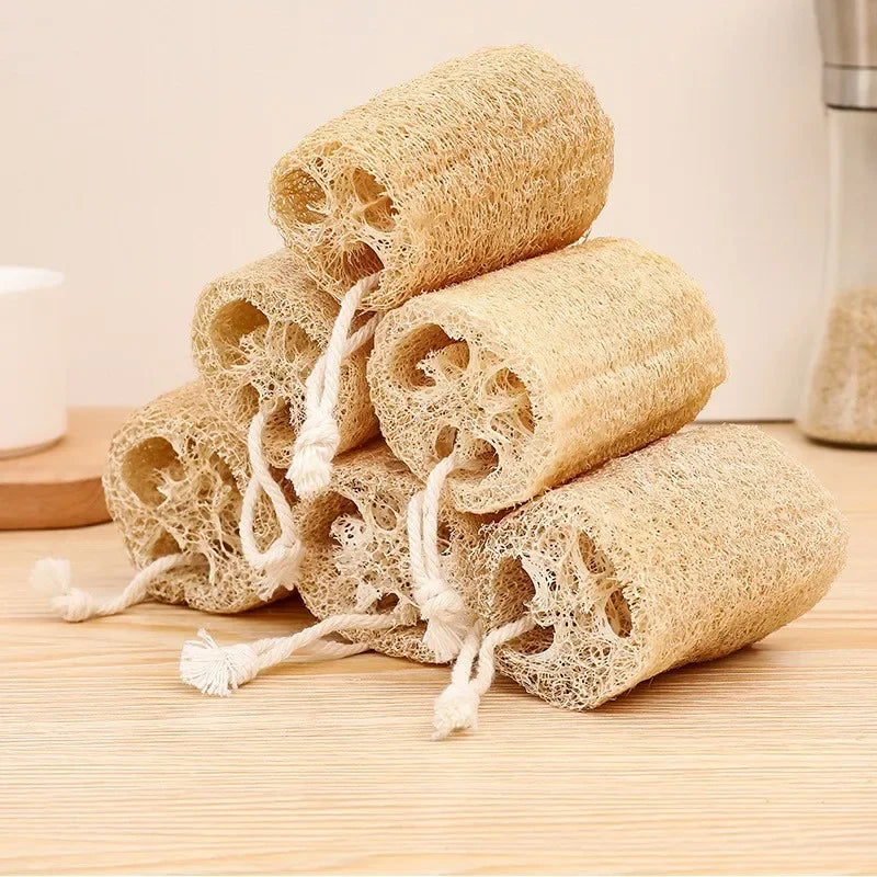 A stack of natural loofah exfoliating body sponges with hanging rope on a wooden surface.
