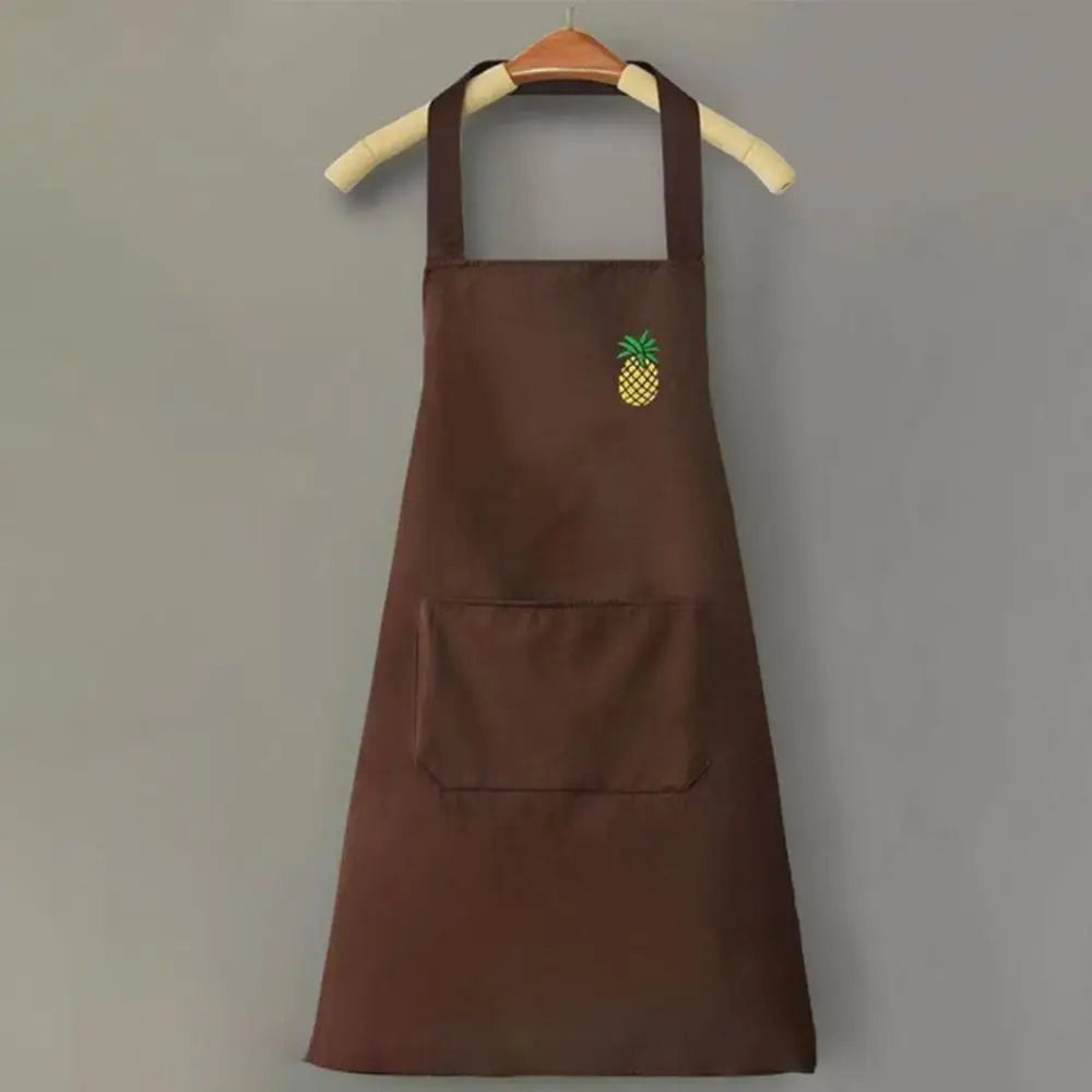 A dark brown chef apron hanging on a wooden hanger with a small yellow pineapple embroidered on the chest.