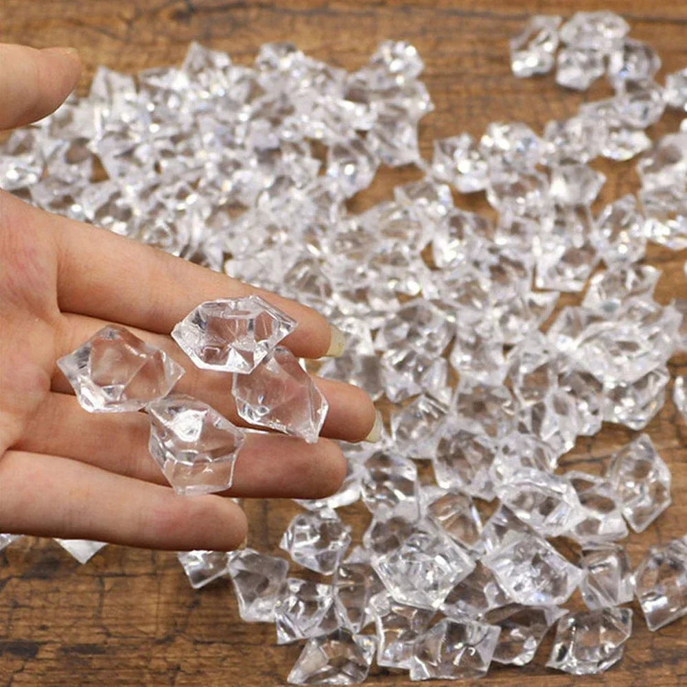 A hand holds clear crystal crushed ice stones scattered on a wooden surface.