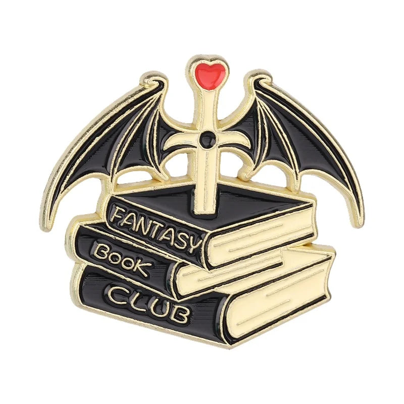 Insignia de esmalte dorado y negro con una cruz alada de murciélago sobre un libro abierto etiquetado 'Fantasy Book Club'