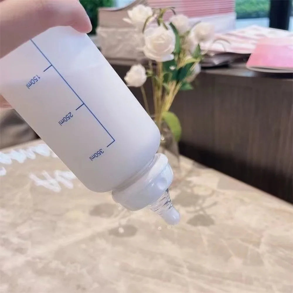 A white water bottle with volume markings is held by a hand, set against a blurred background.