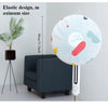 A white electric fan with an elastic design and a protective cover, shown next to a piece of furniture.