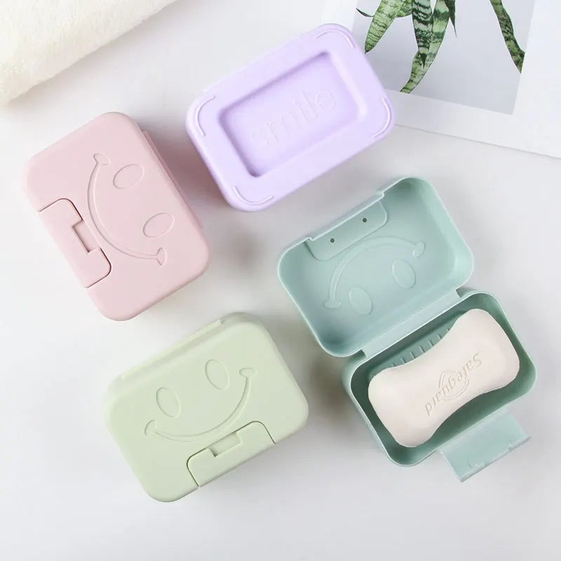 A set of pastel ceramic soap dishes with lids in pink, purple, and mint green colors.
