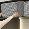A hand is placing a black and white patterned non-woven quilt storage box onto a shelf.