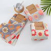A set of pink and orange textured kitchen cleaning cloths with brown labels is displayed on a white surface.