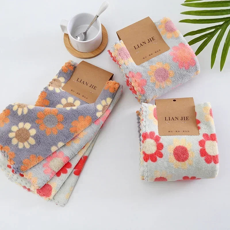 A set of pink and orange textured kitchen cleaning cloths with brown labels is displayed on a white surface.