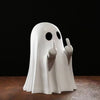 A white ghost statue decoration with raised fingers against a dark background.