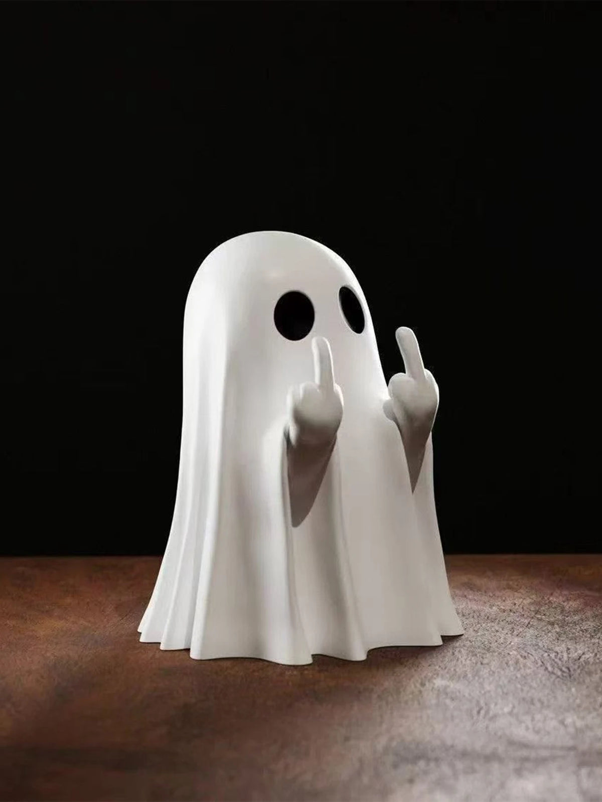 A white ghost statue decoration with raised fingers against a dark background.