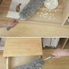 A hand is using a flexible microfiber cleaning duster brush to clean a surface, with loose fibers visible nearby.