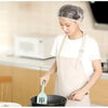A woman wearing a reusable disposable shower cap is using a fork to stir food in a pan.