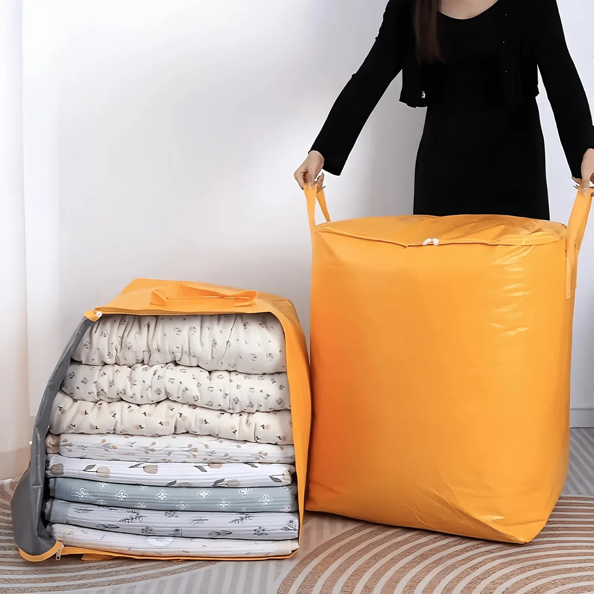 An orange heavy-duty waterproof storage bag is shown filled with rolled white and gray textiles on a wooden floor.