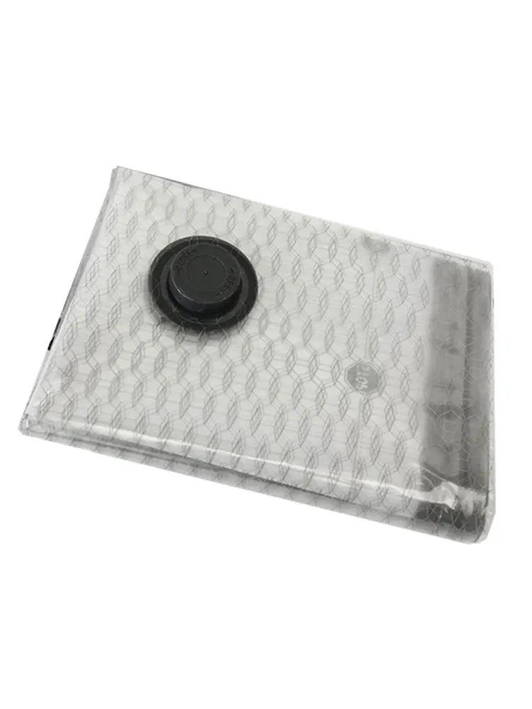 A clear vacuum compression travel bag with a black circular seal on top.