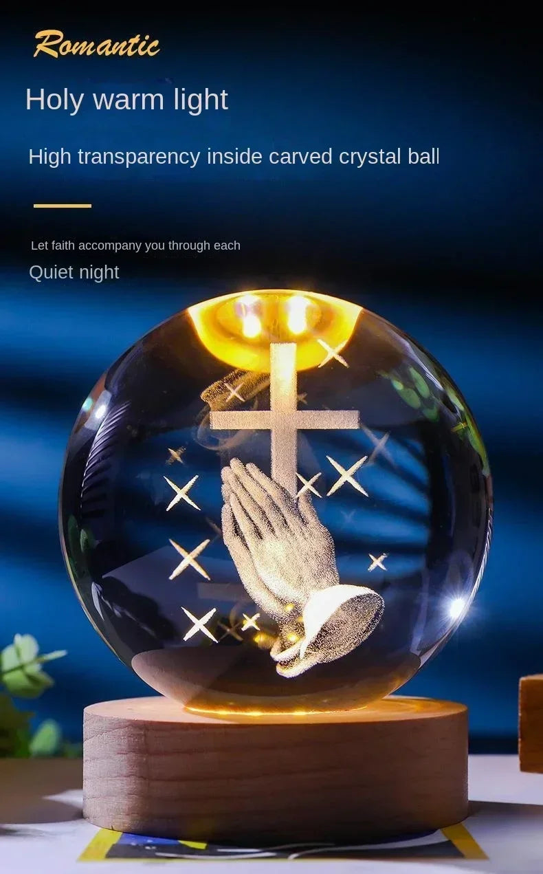 A clear crystal ball with a carved cross and praying hands inside, illuminated by warm light.