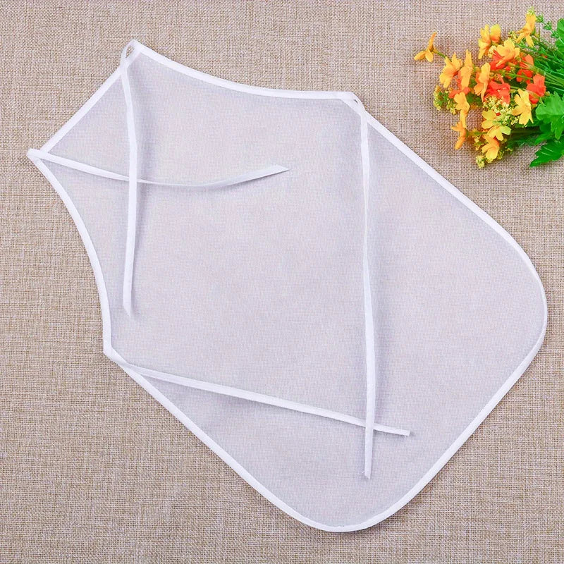 A light gray non-woven craft apron with ties is displayed on a beige fabric background.