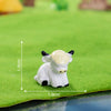 A white resin figurine of a Highland cow standing on green felt.