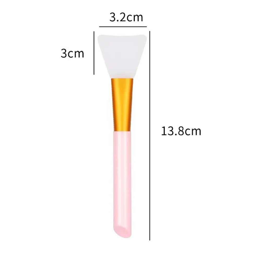 A pink silicone facial mask brush with a white tip and gold handle shown next to dimension lines.