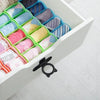 A white cabinet door features silicone self-adhesive lifters in various colors and patterns for easy opening.