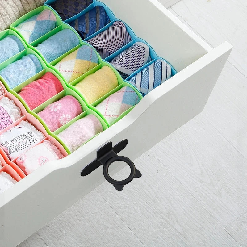 A white cabinet door features silicone self-adhesive lifters in various colors and patterns for easy opening.