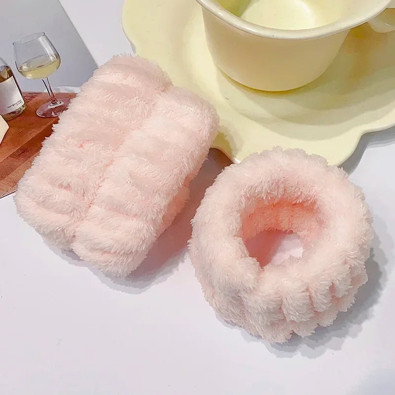 A set of pink microfiber wrist sweatbands for face washing and skincare placed on a white surface.