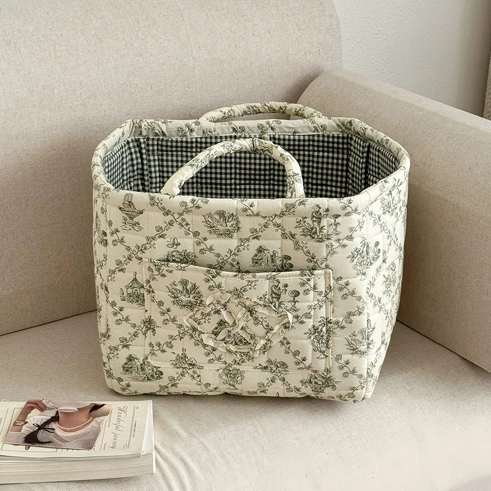 A vintage floral storage basket with a lid and handle, featuring a light cream background with green botanical patterns.