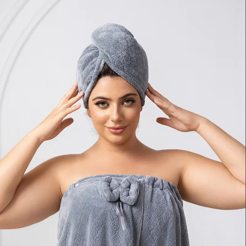 A woman wearing a gray fuzzy wrap robe and turban set, posing with her hands on her head.