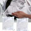 A hand is placing a white mesh bag into a washing machine drum for portable shoe washing.