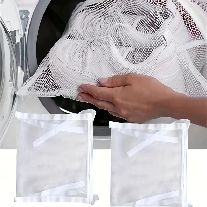A hand is placing a white mesh bag into a washing machine drum for portable shoe washing.